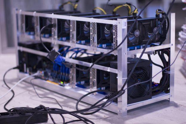 A miner inspecting a mining rig, emphasizing the need for expertise in maintaining and optimizing mining hardware.